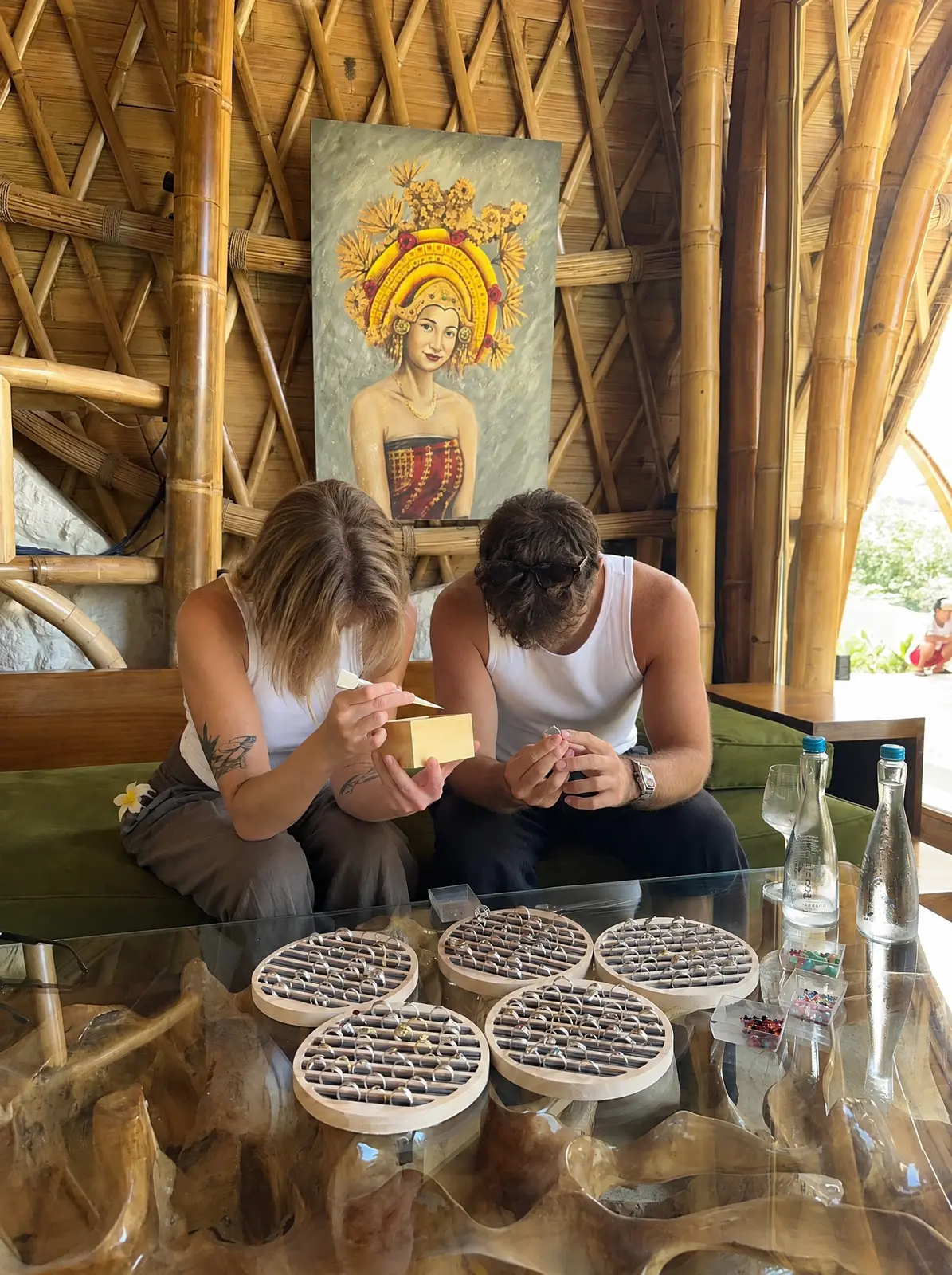 Two guests choosing silver rings under a painting of a Balinese dancer in the bamboo house