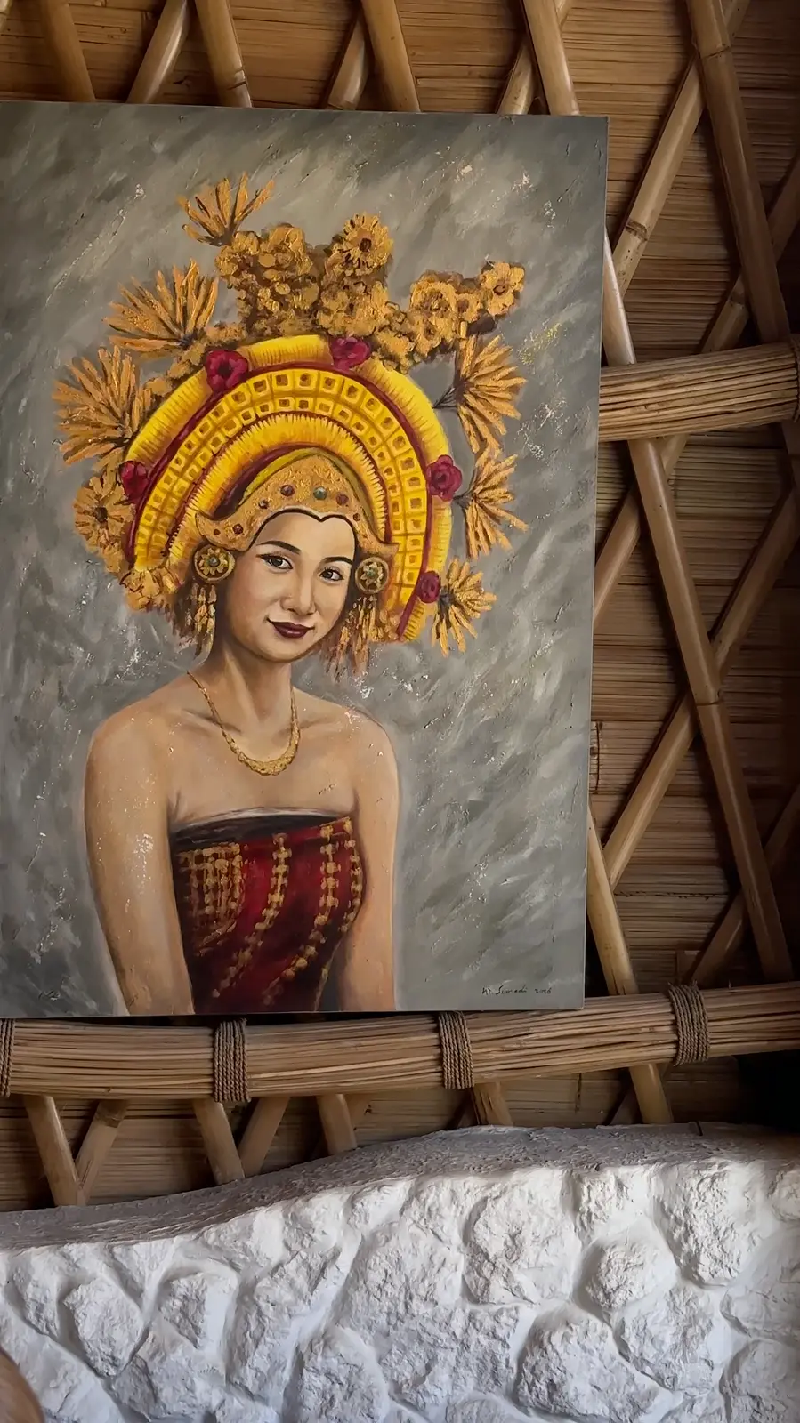 A painting of a Balinese dancer in a golden headdress on a bamboo wall