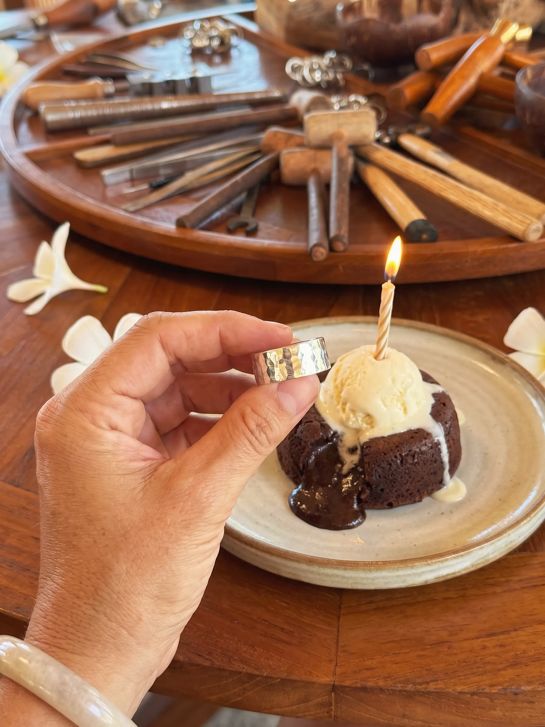 A hand-made silver ring and a birthday lava cake with one candle at the teak workbench