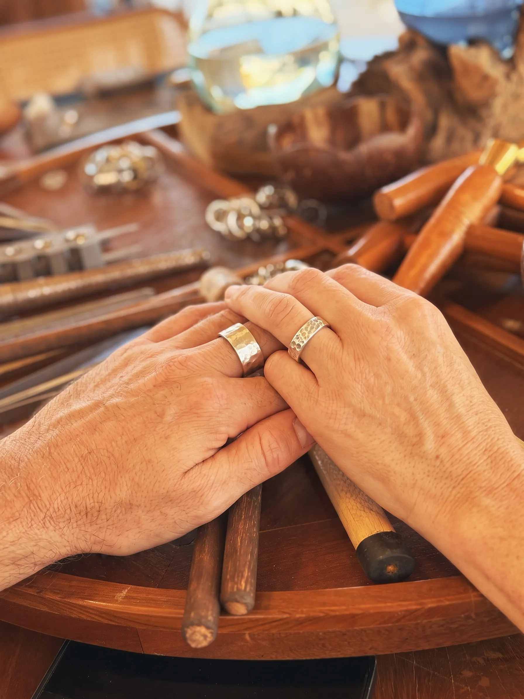 Two hands together, each wearing a new hammered silver ring