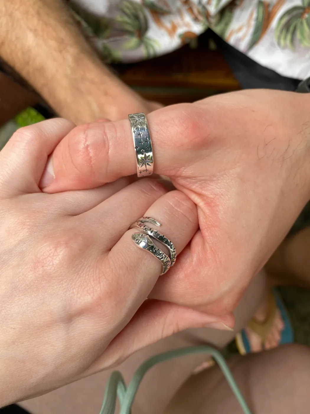 Two hands together, each wearing a silver ring made in the Couple Silver Class
